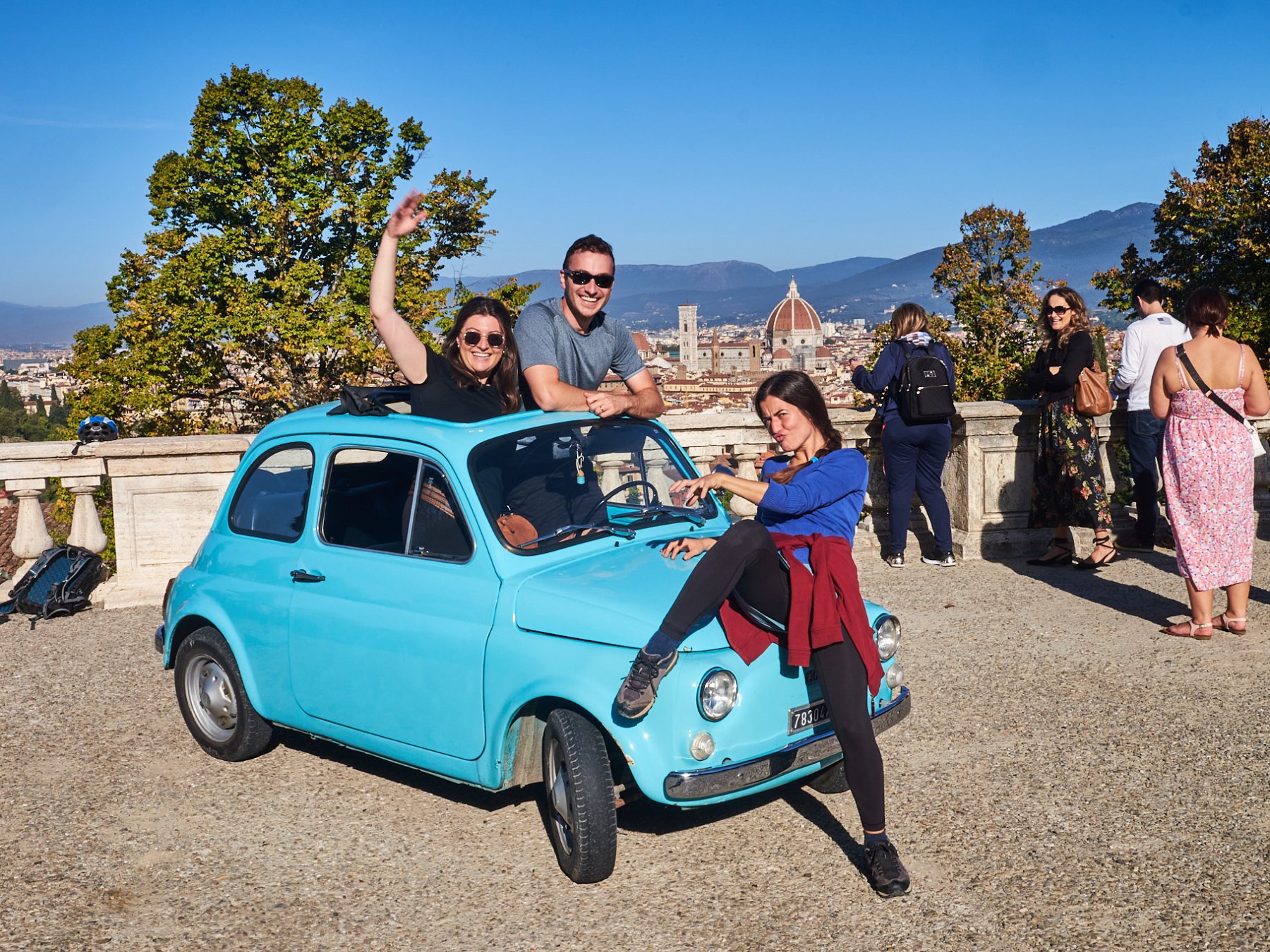 a group of people standing on top of a car posing for the camera