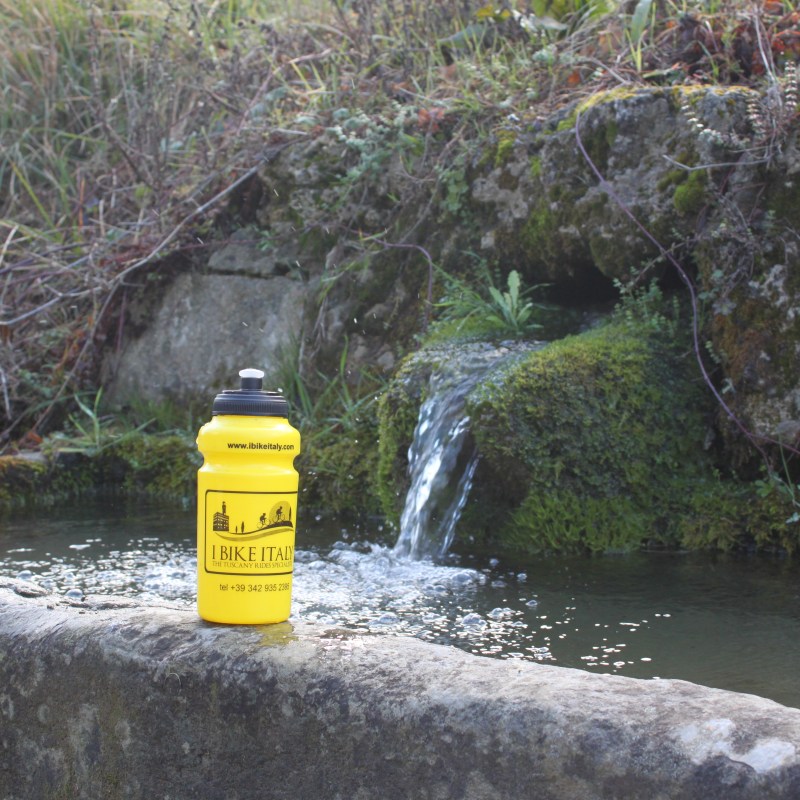 yellow waterbottle next to water in nature in Tuscany