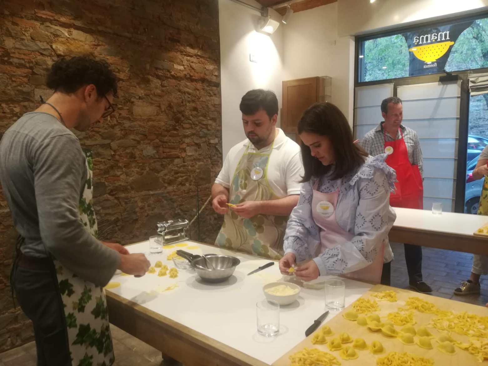 a man and woman cooking pasta on a table