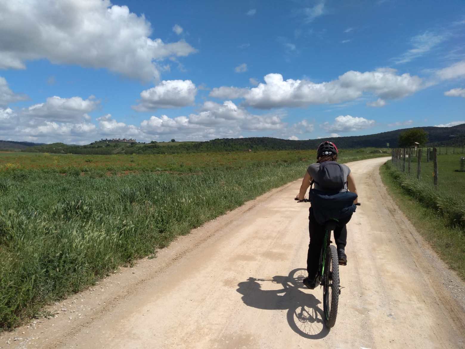 person riding bike on dirt road next to beautiful green nature at Francigena trail