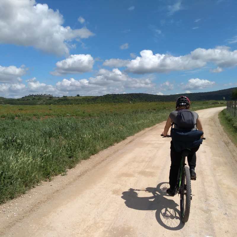 person riding bike on dirt road next to beautiful green nature at Francigena trail