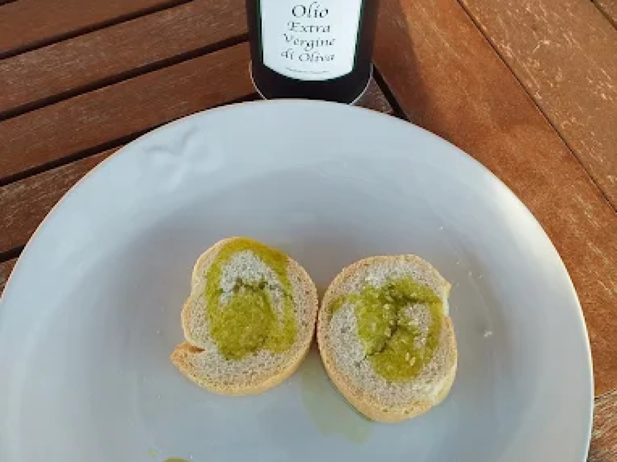 Plate with bread slices and olive oil, bottle of olive oil in background.