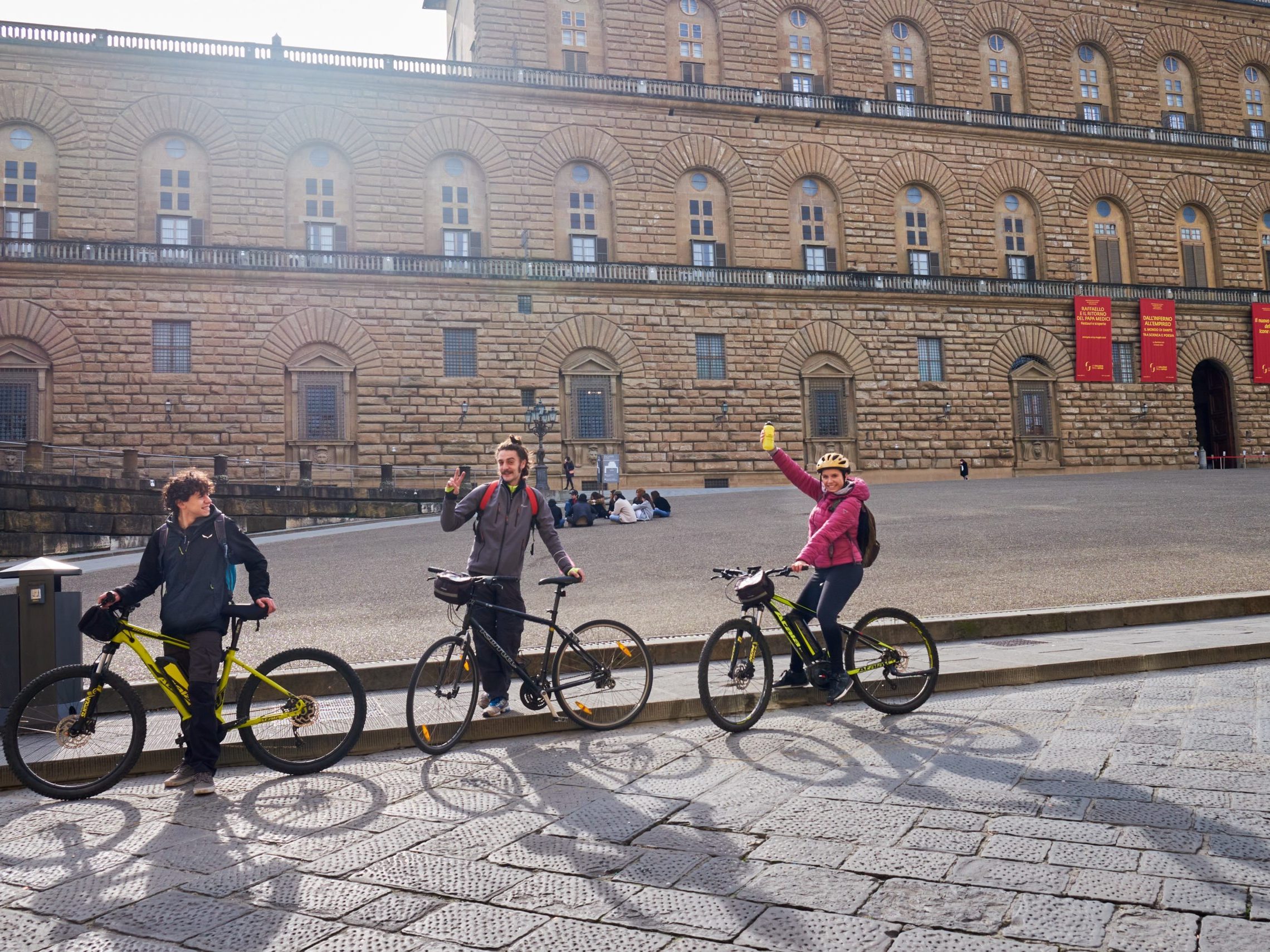 People in bikes in front of stone brick building