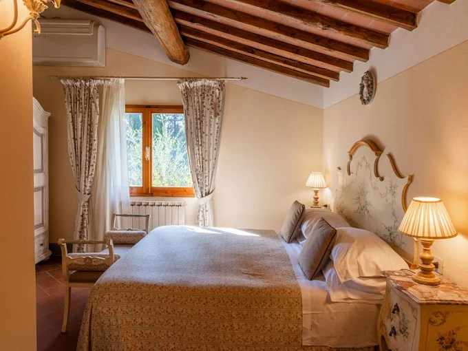 Cozy bedroom with wooden beams, a window, and elegant bedding.