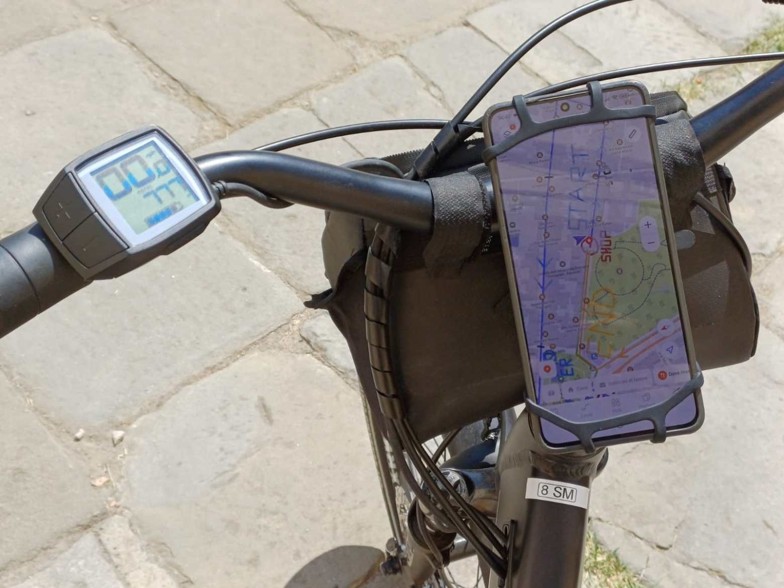 Bicycle handlebars with a smartphone displaying a map and a digital speedometer.