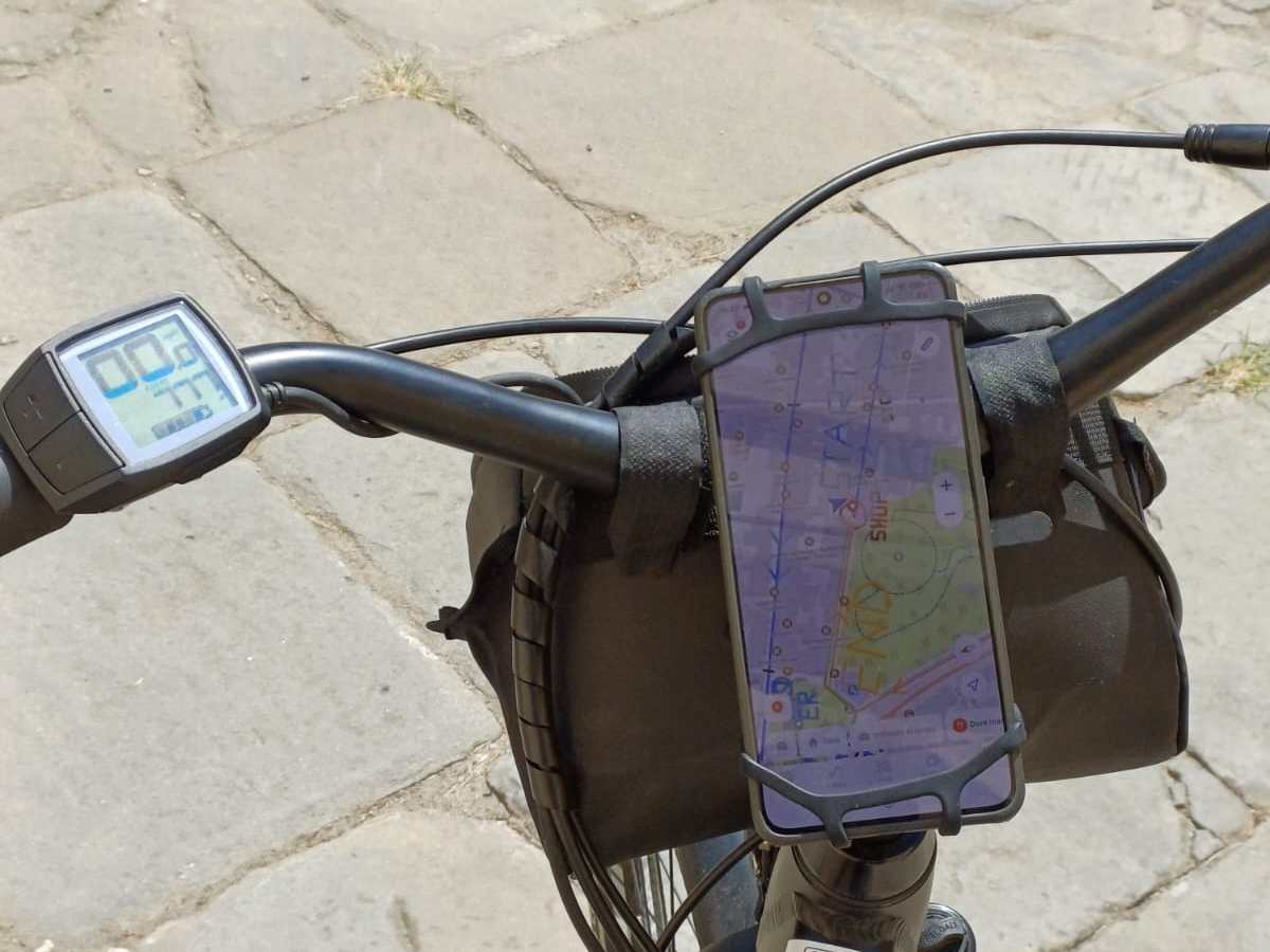 Bicycle handlebars with mounted phone displaying a map and a speedometer.
