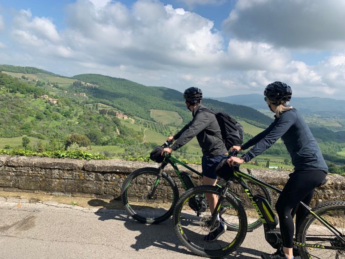 a person riding a bike down a dirt road looking in Italian landscape