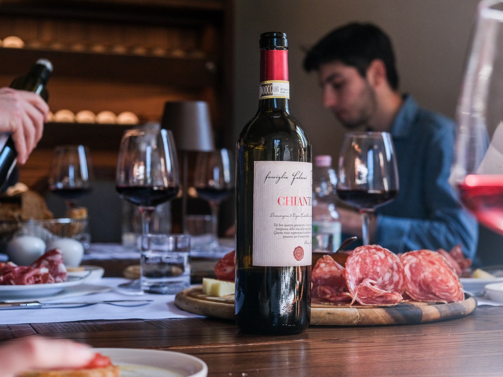 a person holding a bottle of wine on a table