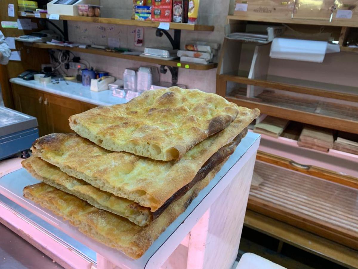 Stack of flatbreads on countertop in a bakery setting.