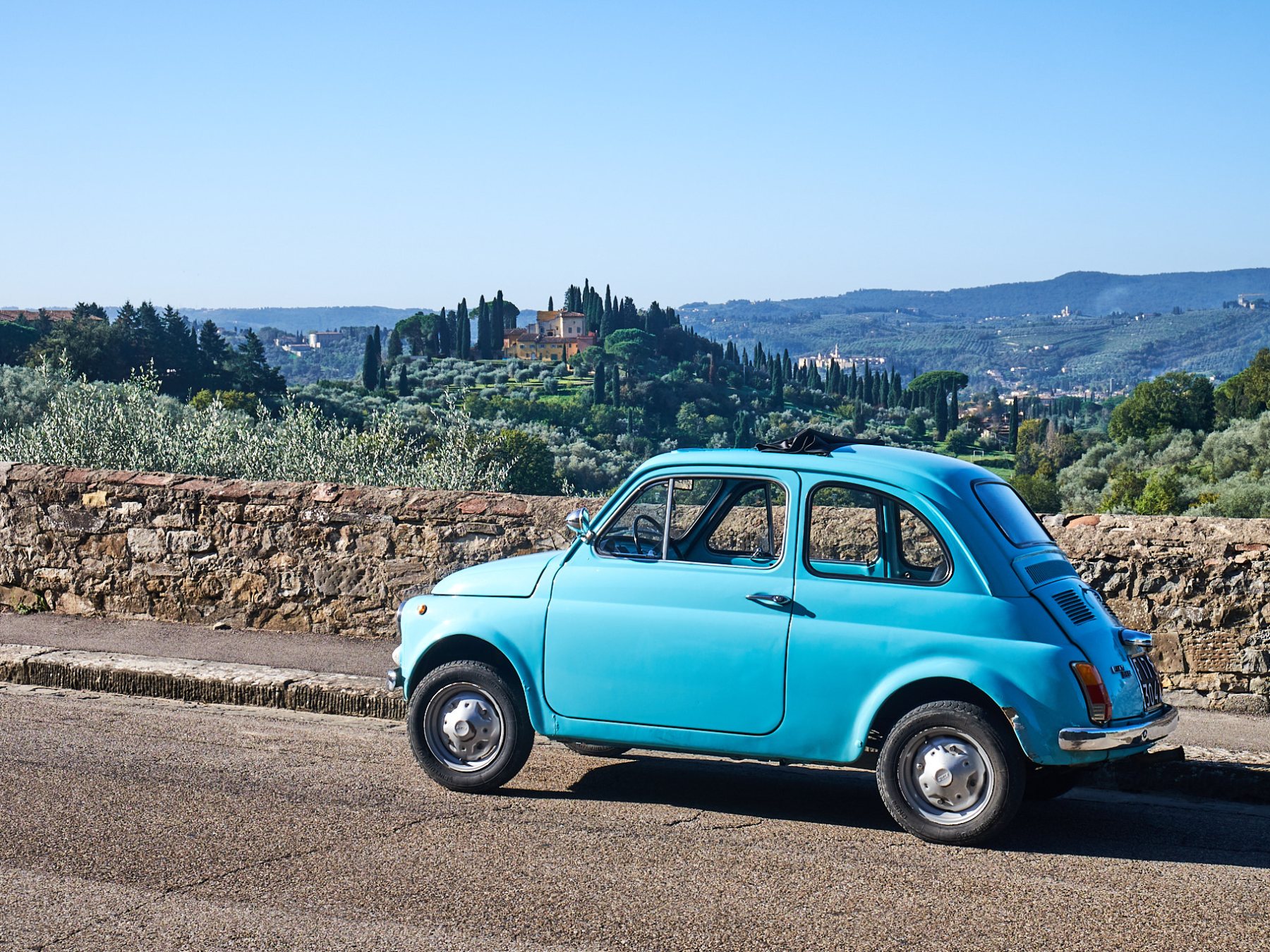 a truck is parked in front of a blue car on a dirt road