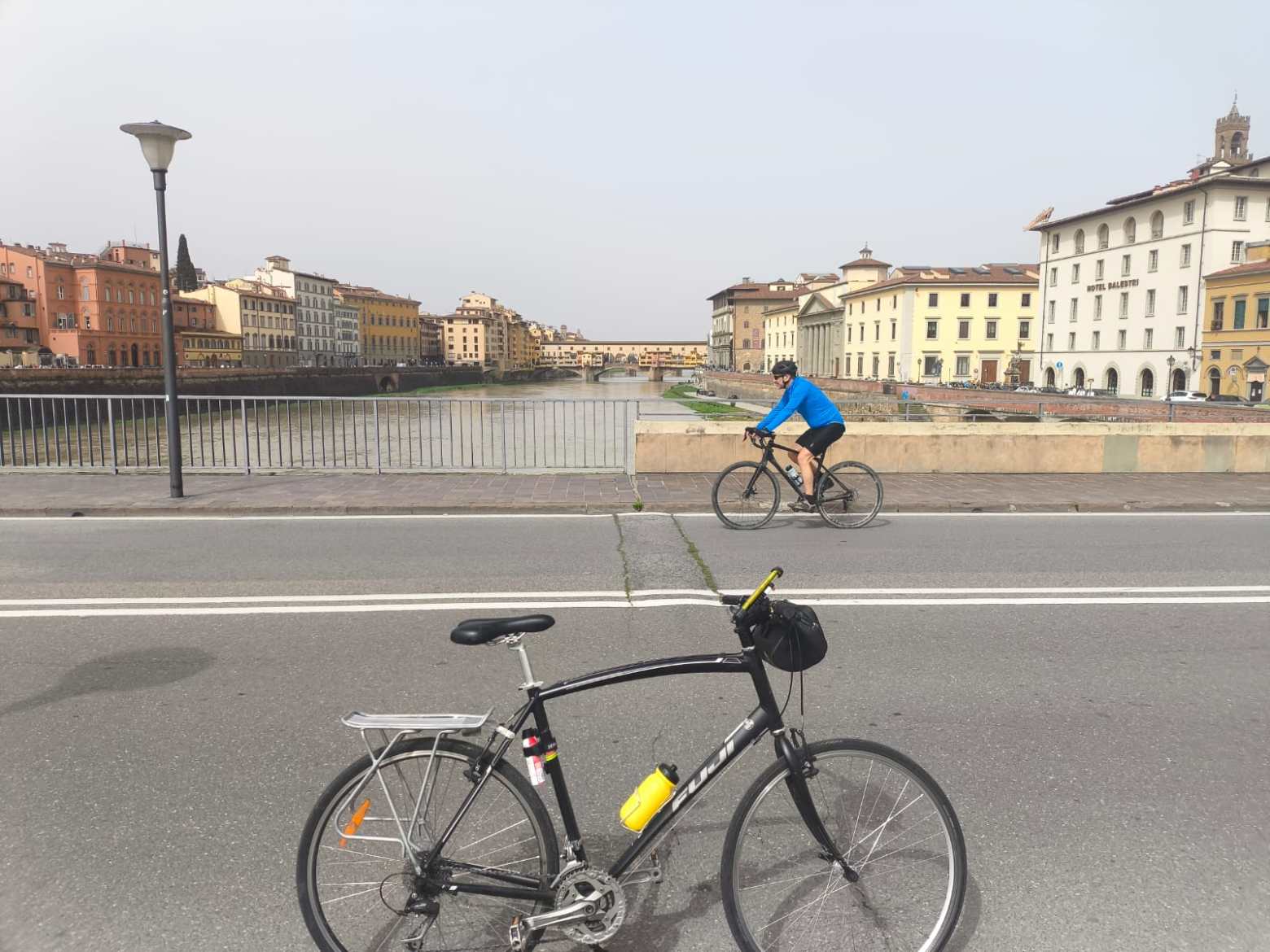 Bicycles on a bridge over a river with colorful buildings in the background.